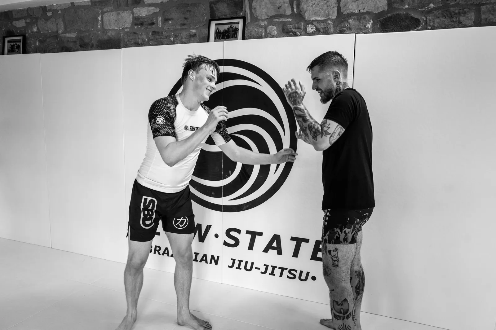 Two training partners laughing during a standing grappling exchange at Flow State BJJ in Barnsley.
